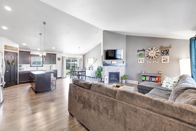 582 Clay St, Wrightstown, WI 54180 - living area with lofted ceiling, light wood-style flooring, a stone fireplace, a chandelier, and recessed lighting