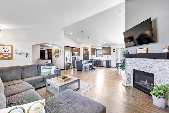 582 Clay St, Wrightstown, WI 54180 - living area with light wood-type flooring, arched walkways, a fireplace, high vaulted ceiling, and recessed lighting