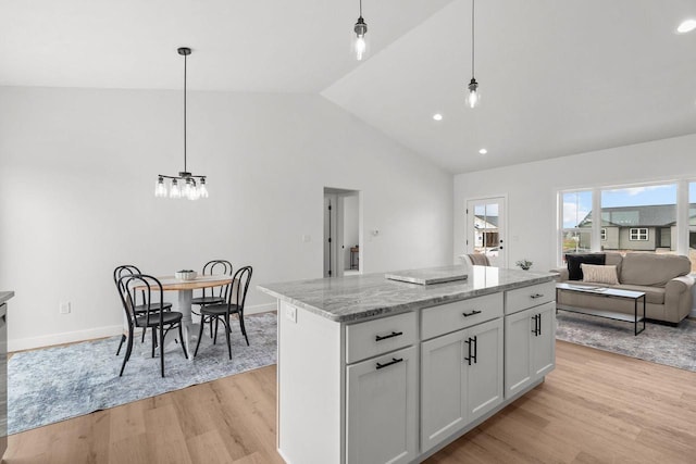 2061 White Dove Ln, Kaukauna, WI 54130 - kitchen with light wood finished floors, vaulted ceiling, a kitchen island, open floor plan, and light stone counters