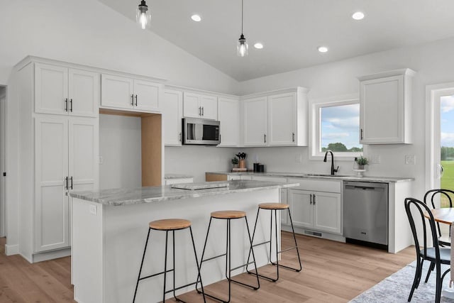 2061 White Dove Ln, Kaukauna, WI 54130 - kitchen featuring appliances with stainless steel finishes, white cabinetry, vaulted ceiling, light wood finished floors, and a kitchen island