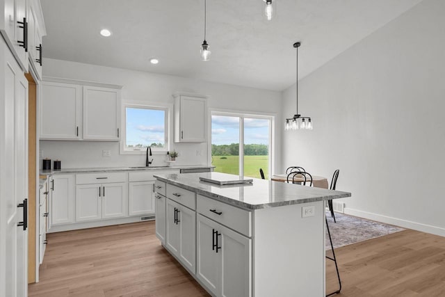 2061 White Dove Ln, Kaukauna, WI 54130 - kitchen with a kitchen island, light wood-style flooring, white cabinets, pendant lighting, and recessed lighting