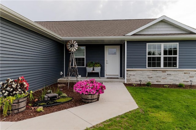 406 S Birch St, Marshfield, WI 54449 - property entrance featuring covered porch, a yard, a shingled roof, and stone siding