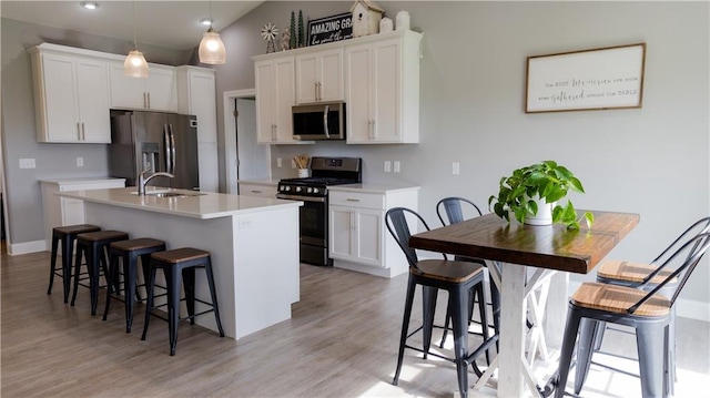 406 S Birch St, Marshfield, WI 54449 - kitchen with appliances with stainless steel finishes, a kitchen breakfast bar, light wood-style flooring, an island with sink, and light countertops