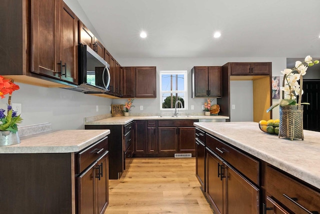 997 E Sunnyview Rd, Oshkosh, WI 54901 - kitchen featuring stainless steel microwave, light wood finished floors, light countertops, dark brown cabinets, and recessed lighting