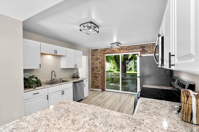 907 Lawe St, Kaukauna, WI 54130 - kitchen featuring stainless steel appliances, light wood-style flooring, brick wall, white cabinets, and light stone countertops