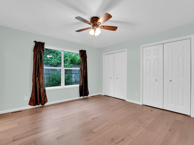 8300 Fishman Rd, Burlington, WI 53105 - unfurnished bedroom featuring multiple closets, light wood-style flooring, and ceiling fan