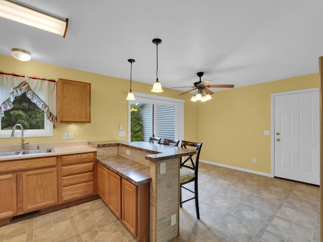 8300 Fishman Rd, Burlington, WI 53105 - kitchen with a peninsula, a breakfast bar area, a ceiling fan, decorative light fixtures, and brown cabinets