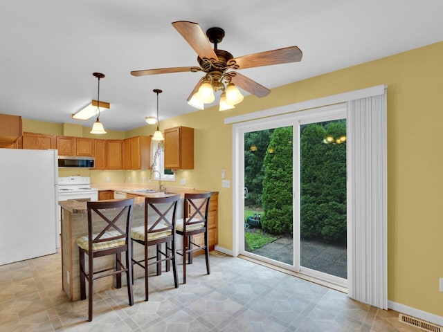 8300 Fishman Rd, Burlington, WI 53105 - kitchen featuring white appliances, light countertops, a ceiling fan, hanging light fixtures, and a peninsula