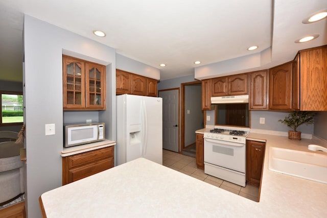 8535 N 59th St, Brown Deer, WI 53223 - kitchen with white appliances, under cabinet range hood, light countertops, glass insert cabinets, and light tile patterned flooring