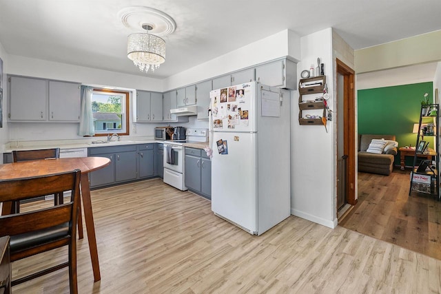 605 E 10th St, Fond Du Lac, WI 54935 - kitchen with white appliances, gray cabinetry, under cabinet range hood, light wood-style floors, and light countertops