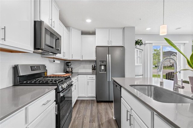 7243 Fall Dr, Hugo, MN 55038 - kitchen featuring stainless steel appliances, dark wood finished floors, white cabinets, light stone countertops, and recessed lighting
