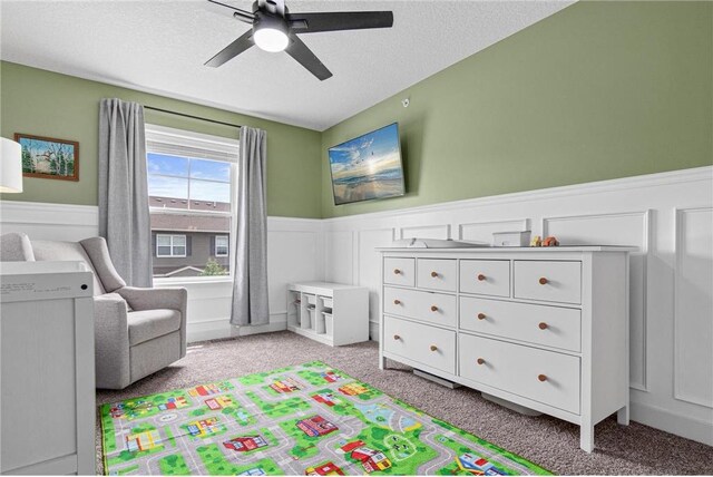 7243 Fall Dr, Hugo, MN 55038 - bedroom featuring light carpet, wainscoting, a ceiling fan, a textured ceiling, and a decorative wall
