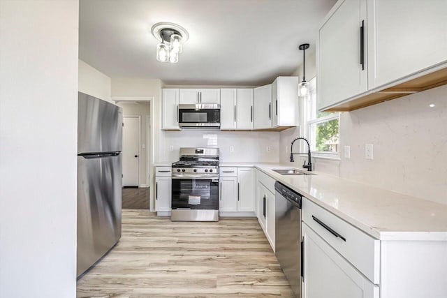 2316 W Rohr Ave, Milwaukee, WI 53209 - kitchen with appliances with stainless steel finishes, light wood-style floors, white cabinets, and pendant lighting