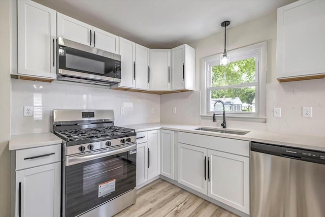 2316 W Rohr Ave, Milwaukee, WI 53209 - kitchen featuring stainless steel appliances, light countertops, white cabinetry, pendant lighting, and light wood-style flooring