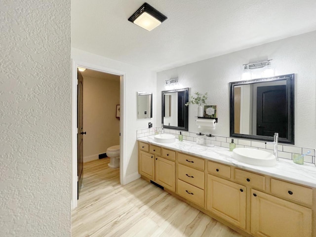 431 Limestone St, Kiel, WI 53042 - full bath with double vanity, wood finished floors, backsplash, and a textured wall