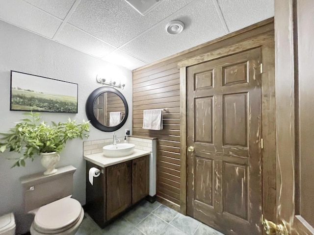 431 Limestone St, Kiel, WI 53042 - bathroom featuring vanity, wooden walls, a drop ceiling, and tile patterned floors