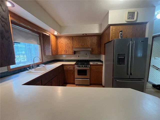 514 S Robert St, Grantsburg, WI 54840 - kitchen with stainless steel appliances, under cabinet range hood, brown cabinetry, light countertops, and backsplash