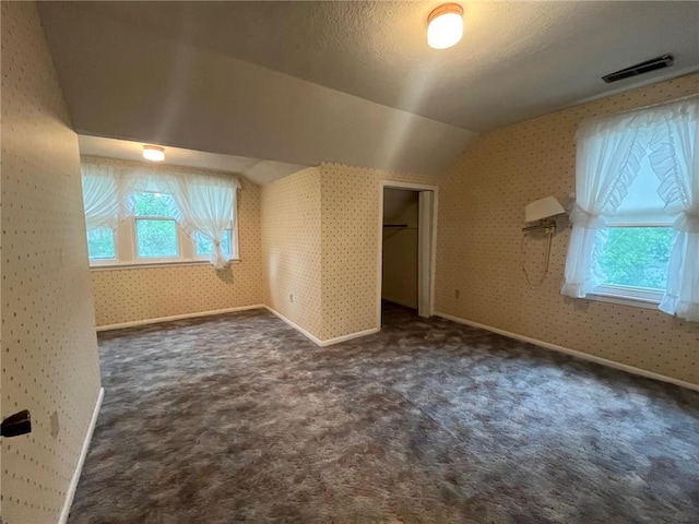 514 S Robert St, Grantsburg, WI 54840 - unfurnished bedroom featuring lofted ceiling, dark colored carpet, a closet, and wallpapered walls
