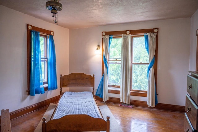 318 Tremont St, Mauston, WI 53948 - bedroom featuring wood finished floors, multiple windows, and a textured ceiling