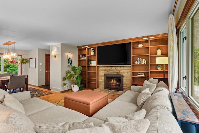 5706 Tolman Ter, Madison, WI 53711 - living room with wood finished floors, a chandelier, a stone fireplace, and plenty of natural light