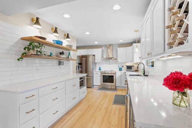5706 Tolman Ter, Madison, WI 53711 - kitchen featuring stainless steel appliances, wall chimney exhaust hood, tasteful backsplash, light wood-style floors, and white cabinetry