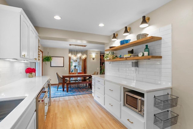 5706 Tolman Ter, Madison, WI 53711 - kitchen with appliances with stainless steel finishes, light wood-style flooring, tasteful backsplash, white cabinetry, and decorative light fixtures