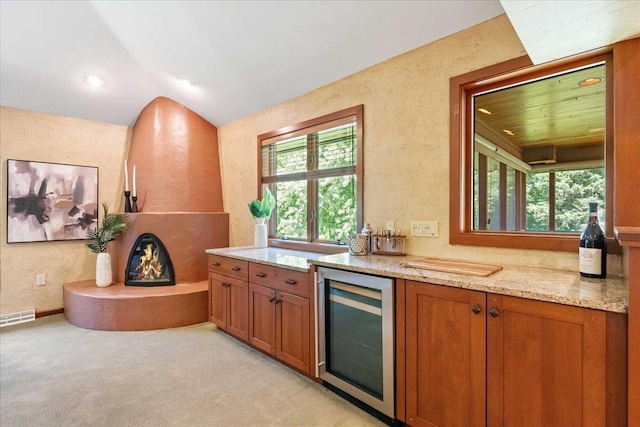 5870 Persimmon Dr, Fitchburg, WI 53711 - kitchen with beverage cooler, brown cabinets, light stone counters, lofted ceiling, and light carpet