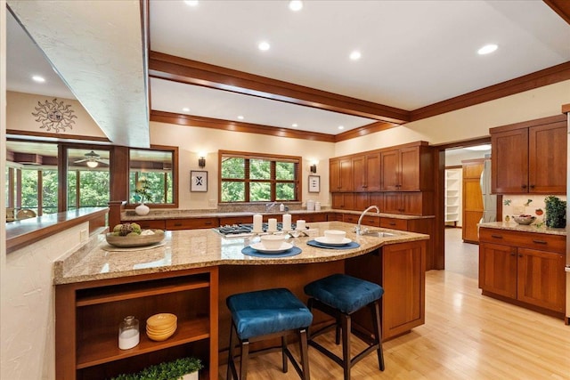 5870 Persimmon Dr, Fitchburg, WI 53711 - kitchen with gas cooktop, crown molding, light stone counters, brown cabinetry, and healthy amount of natural light