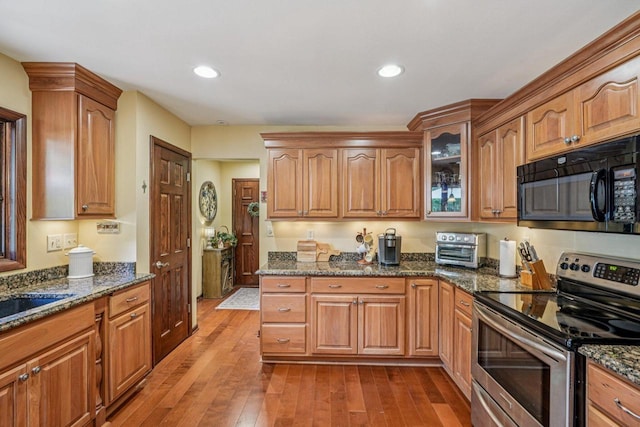 S46W22428 Tansdale Rd, Waukesha, WI 53189 - kitchen with black microwave, stainless steel electric range, dark stone countertops, wood-type flooring, and glass insert cabinets