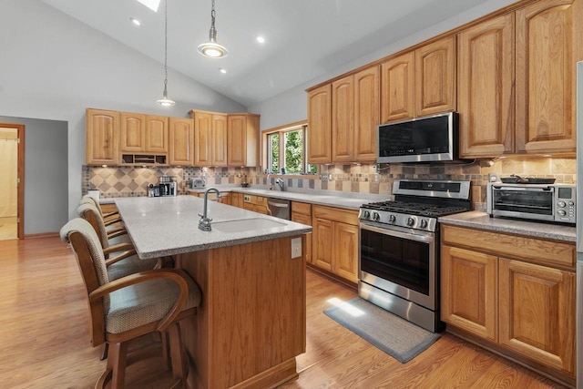 1201 Lance Dr, Twin Lakes, WI 53181 - kitchen with stainless steel appliances, light wood finished floors, a kitchen breakfast bar, decorative light fixtures, and recessed lighting