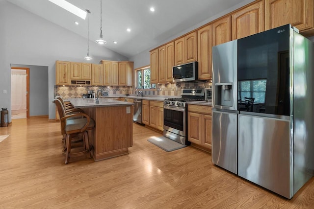 1201 Lance Dr, Twin Lakes, WI 53181 - kitchen with stainless steel appliances, a skylight, tasteful backsplash, light wood-style flooring, and an island with sink