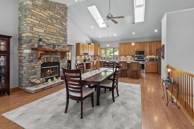 1201 Lance Dr, Twin Lakes, WI 53181 - dining room with a skylight, light wood-style floors, high vaulted ceiling, a fireplace, and ceiling fan