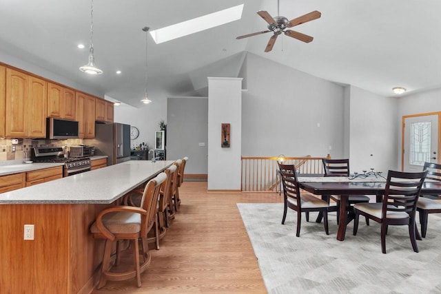 1201 Lance Dr, Twin Lakes, WI 53181 - kitchen with stainless steel appliances, a center island with sink, lofted ceiling, a skylight, and a ceiling fan