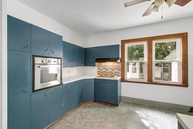 215 W Burns St, Portage, WI 53901 - kitchen featuring oven, blue cabinets, under cabinet range hood, tasteful backsplash, and ceiling fan