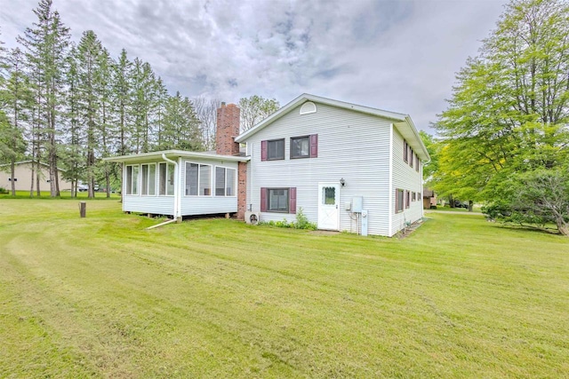 7040 Blonien Ave, Rudolph, WI 54475 - back of house with a chimney, a sunroom, and a lawn