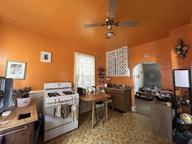 2467 N Bartlett Ave Unit 2467A, Milwaukee, WI 53211 - kitchen with white range with gas stovetop, a ceiling fan, arched walkways, light floors, and light countertops