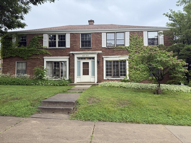 6533 W Center St, Wauwatosa, WI 53210 - view of front of property with brick siding, a front yard, and a chimney