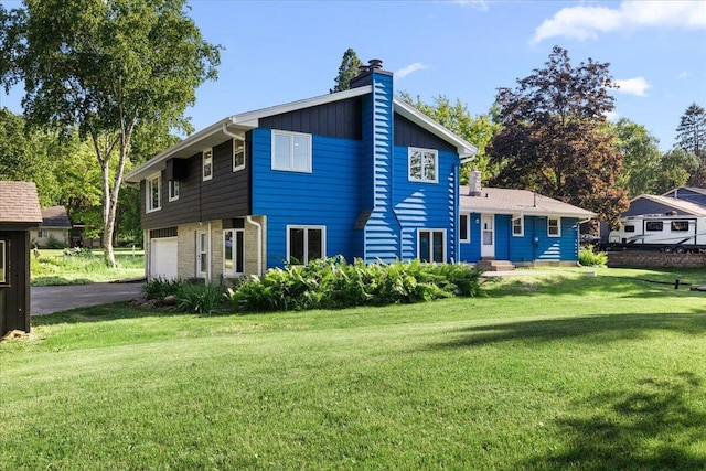 N113W20588 Edgewood Dr, Germantown, WI 53022 - back of house with a chimney, a garage, asphalt driveway, and a lawn
