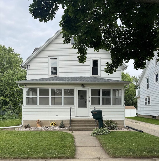 514 Robert St, Fort Atkinson, WI 53538 - traditional style home featuring entry steps, a front lawn, roof with shingles, and a sunroom