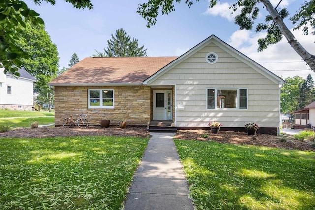 421 Fremont St, Lake Mills, WI 53551 - view of front facade with a front lawn, a shingled roof, and stone siding