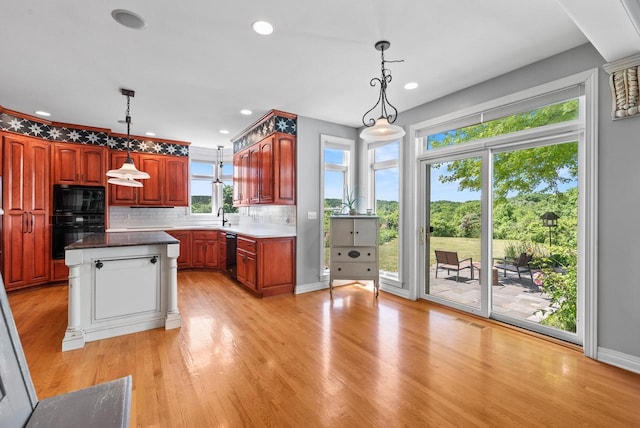 4047 Scenic Rd, Jackson, WI 53037 - kitchen with black appliances, a kitchen island, tasteful backsplash, decorative light fixtures, and light wood finished floors