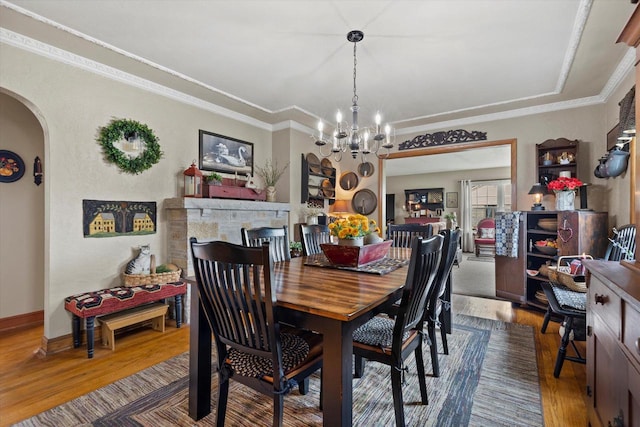 20903 W Main St, Lannon, WI 53046 - dining room featuring arched walkways, wood finished floors, a chandelier, ornamental molding, and a raised ceiling