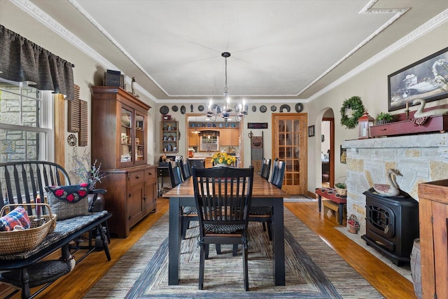 20903 W Main St, Lannon, WI 53046 - dining space featuring wood finished floors, arched walkways, a chandelier, a wood stove, and crown molding