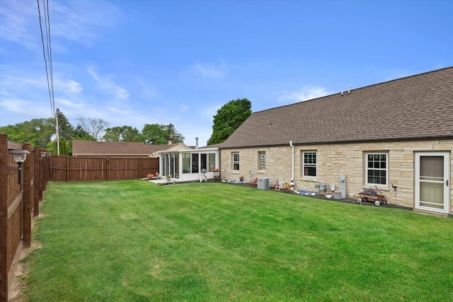20903 W Main St, Lannon, WI 53046 - back of house featuring a sunroom, a fenced backyard, a shingled roof, and stone siding