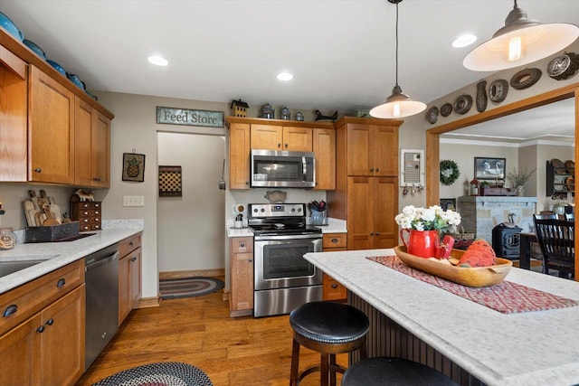 20903 W Main St, Lannon, WI 53046 - kitchen with stainless steel appliances, light wood finished floors, light countertops, a kitchen bar, and decorative light fixtures