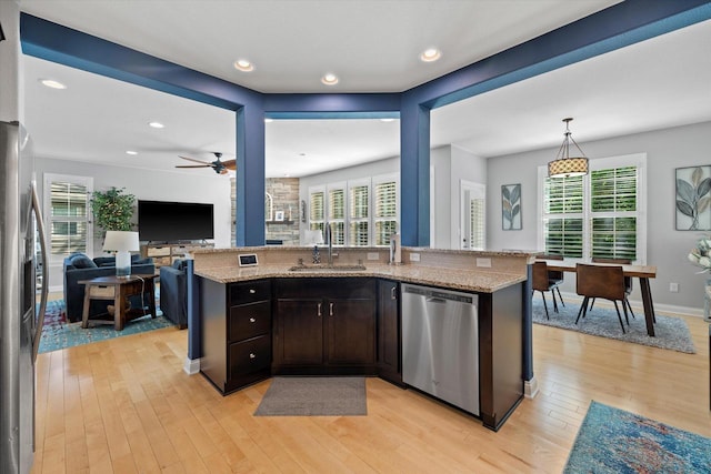 8061 S River Ln, Franklin, WI 53132 - kitchen featuring appliances with stainless steel finishes, light wood finished floors, open floor plan, light stone countertops, and ceiling fan