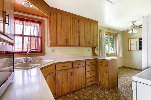 1313 S 26th St, Manitowoc, WI 54220 - kitchen with light countertops, range, ceiling fan, a peninsula, and brown cabinets