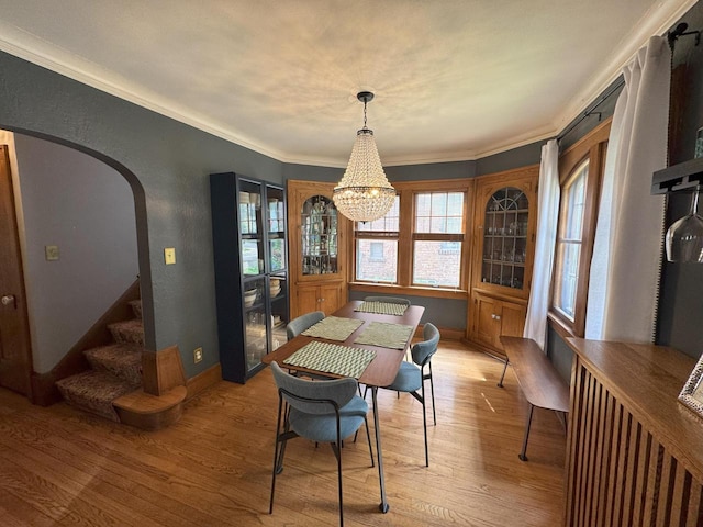 6309 W Mckinley Ave, Wauwatosa, WI 53213 - dining space featuring light wood-style floors, a chandelier, ornamental molding, stairs, and arched walkways
