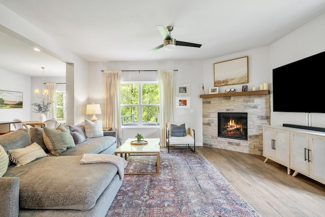309 Paradise Ct, Hartland, WI 53029 - living area featuring wood finished floors, a chandelier, a stone fireplace, and ceiling fan