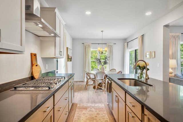 309 Paradise Ct, Hartland, WI 53029 - kitchen with wall chimney exhaust hood, light wood-style floors, a chandelier, stainless steel appliances, and pendant lighting
